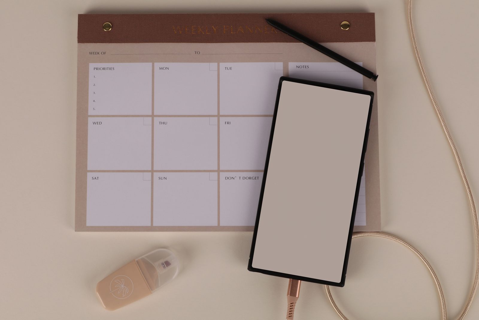Planificador semanal sin fechas con un bolígrafo y un teléfono sobre la mesa.