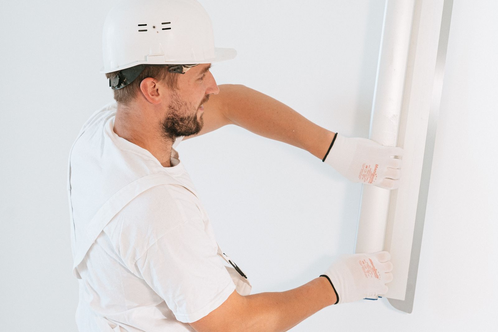 Trabajador con casco y guantes alisando una pared interior.