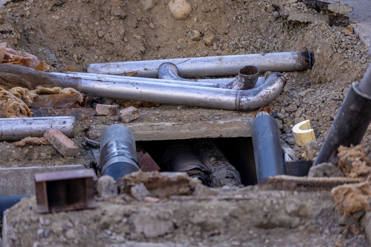 Tuyauteries métalliques et éléments de conduites au milieu d’une excavation de chantier.