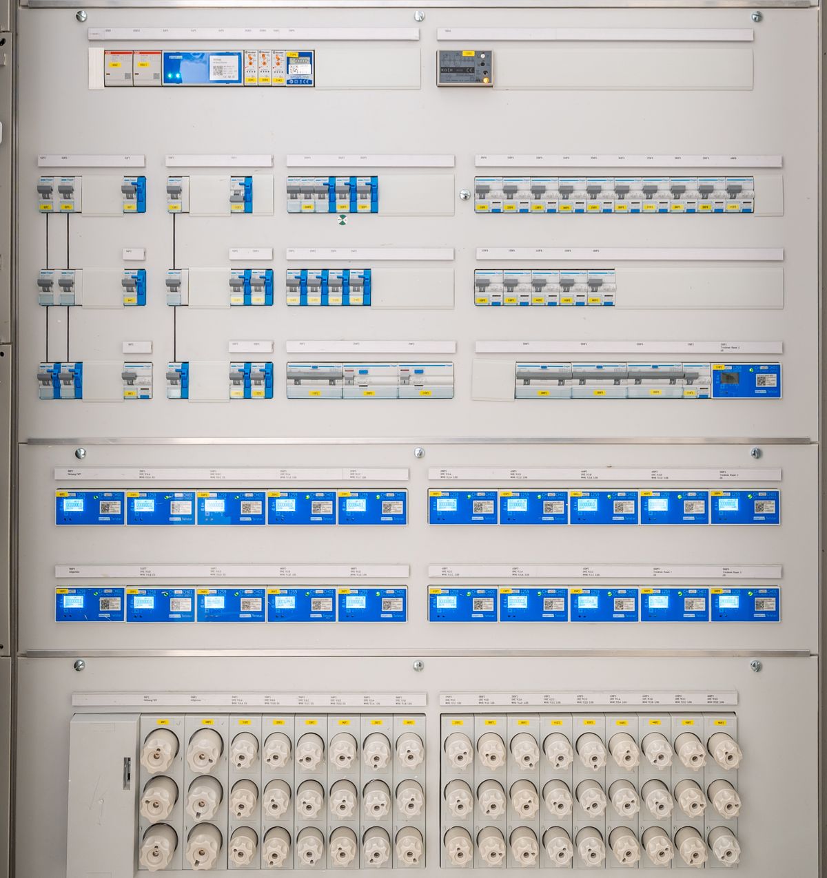 Front of an electrical distribution panel with rows of circuit breakers, meters and protective covers.