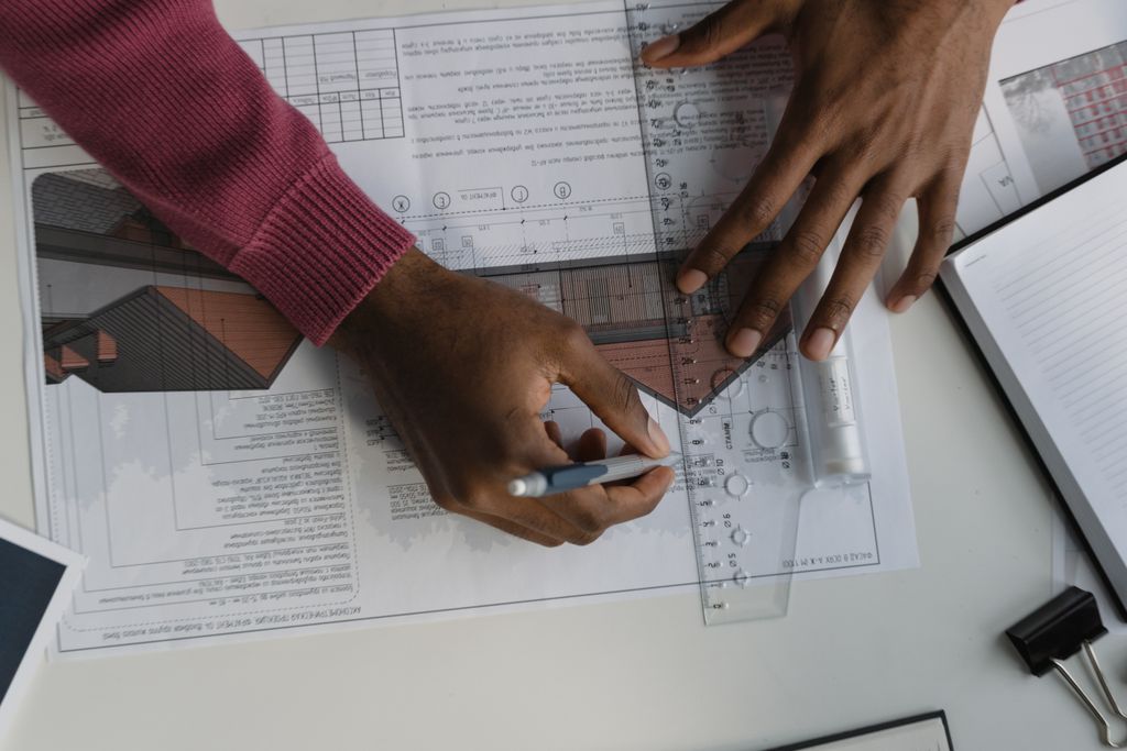 Une personne travaille sur des plans avec une règle.