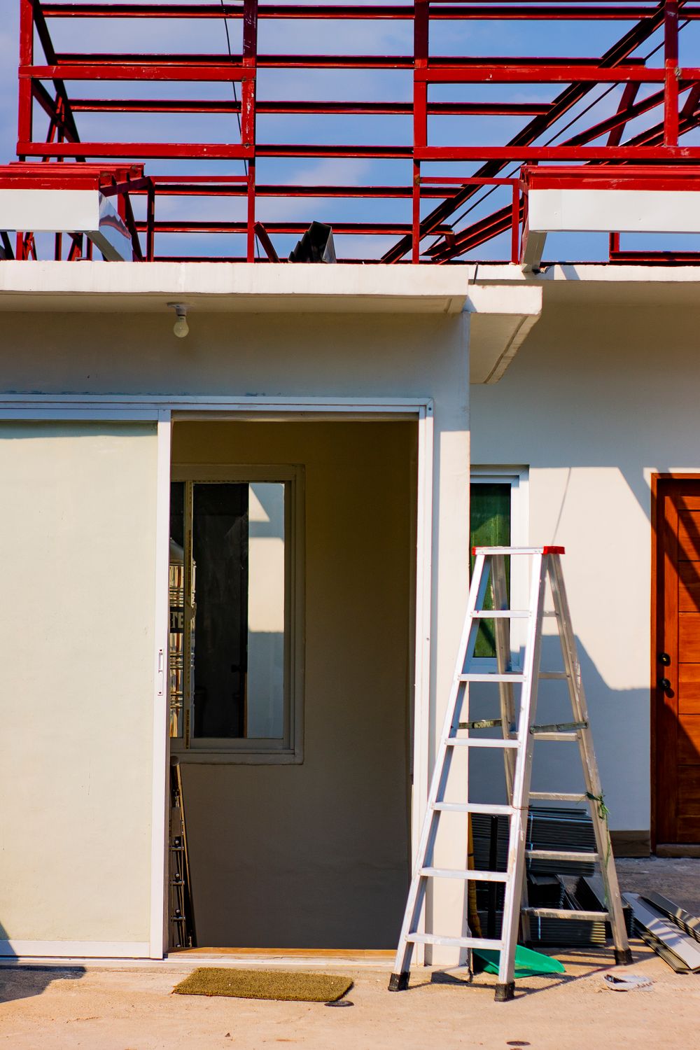 A building under renovation with a ladder and exposed red framing.