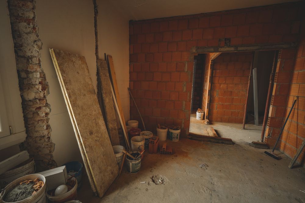 Interior en obras con paredes de ladrillo, cubos y materiales de construcción.